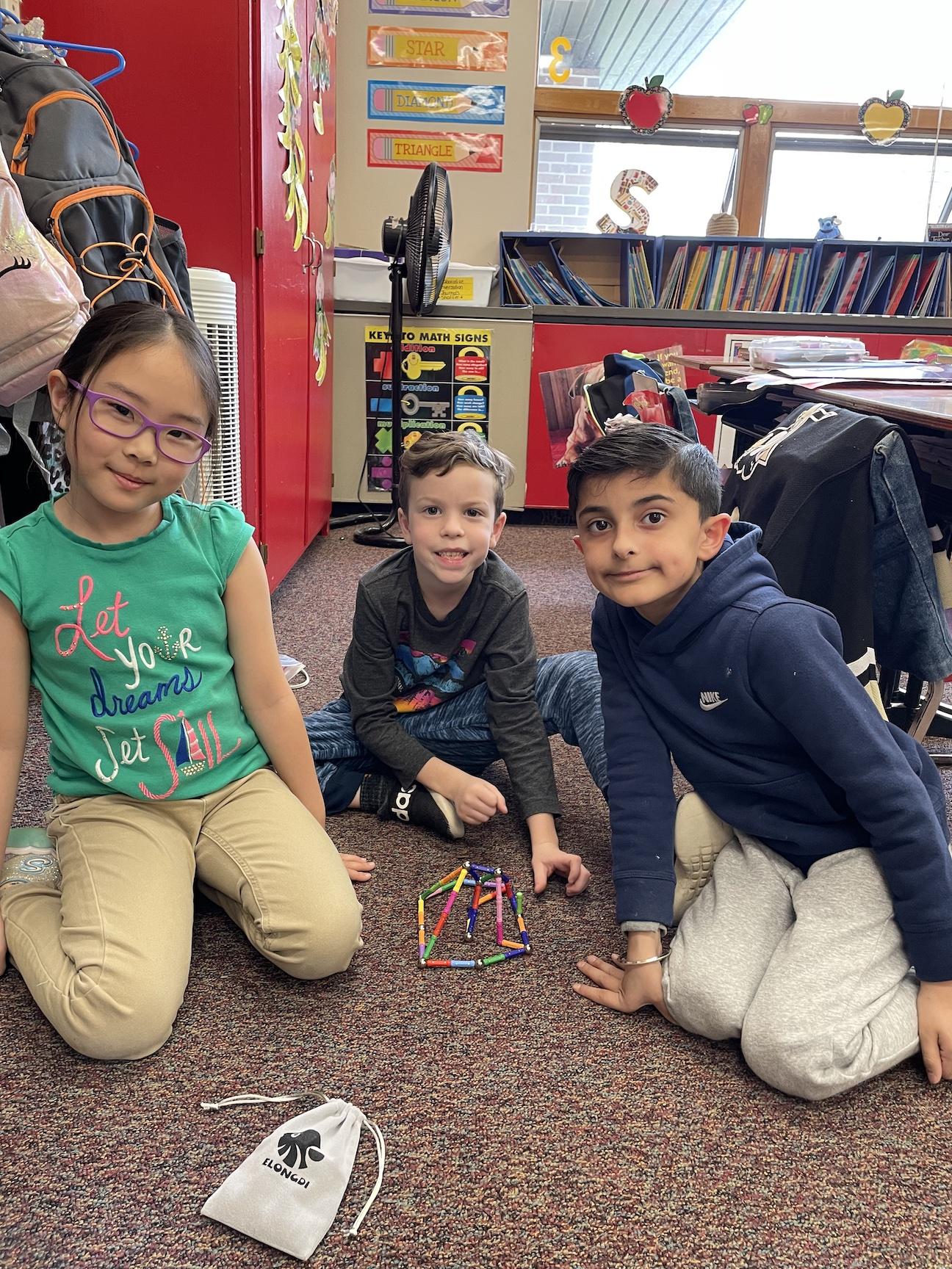 Hannah Jang, Emerson Wright, and Aryan Sidhu build their structure with magnetic sticks