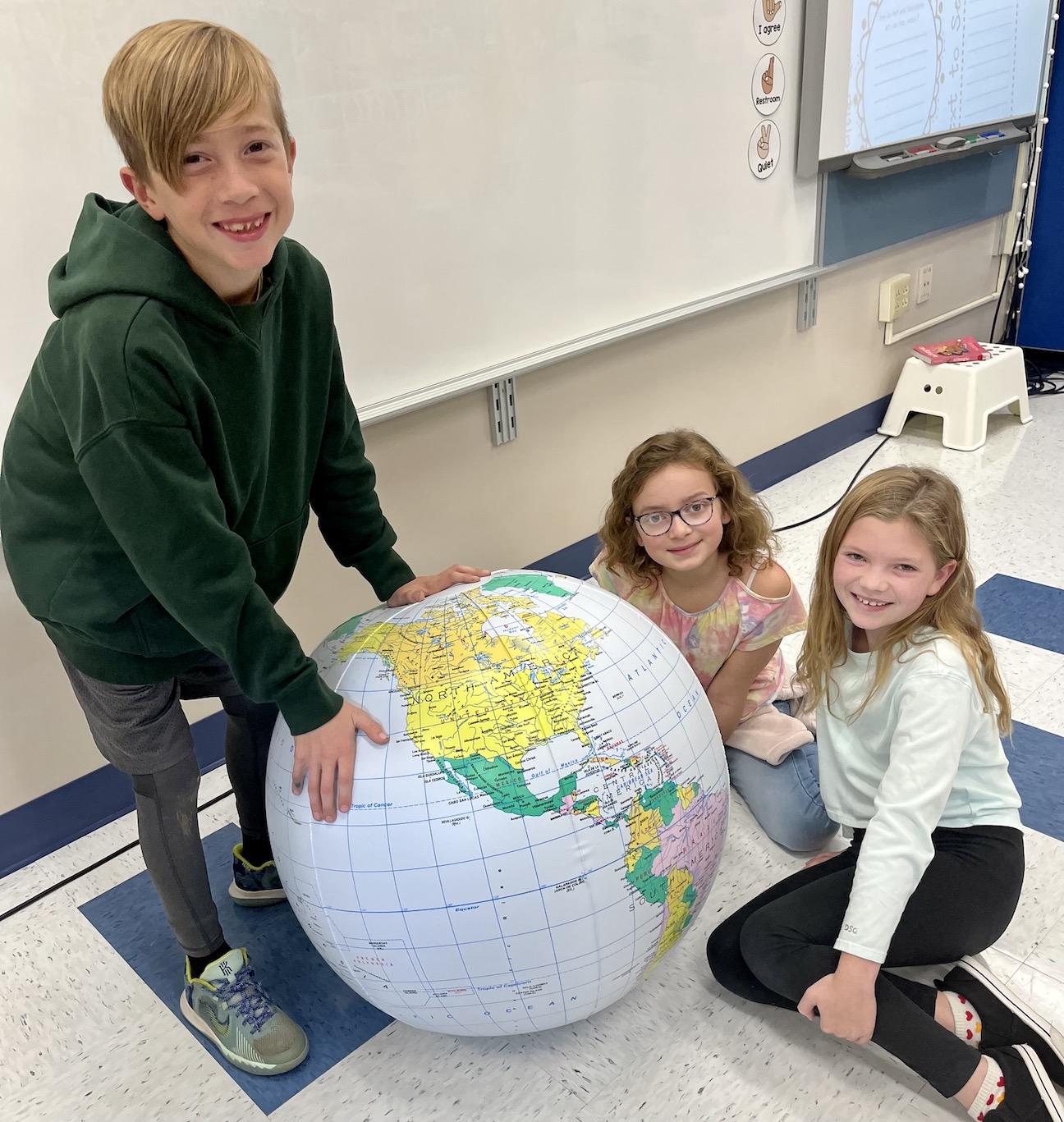 Sawyer Cribbs, Madelyn Renwick, and Scarlett Zemba study countries on the jumbo globe